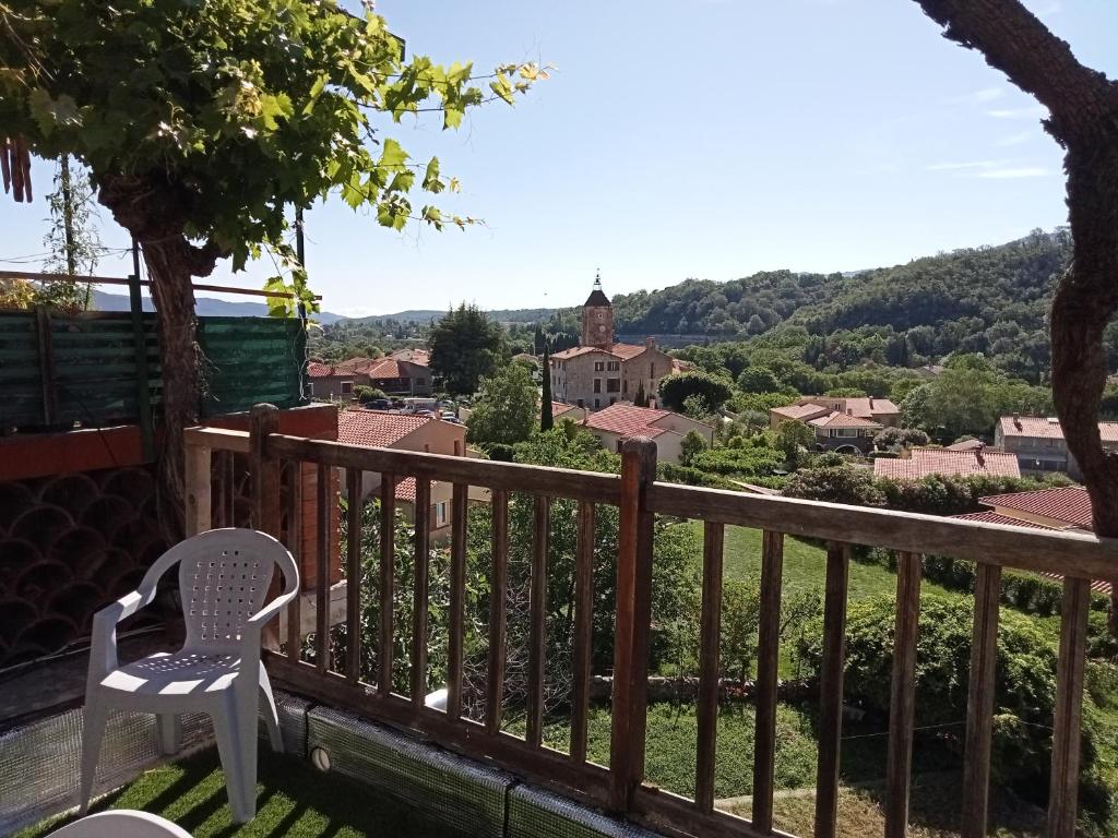 una silla en el balcón con vistas a la ciudad en Petite maison de village, en Ria