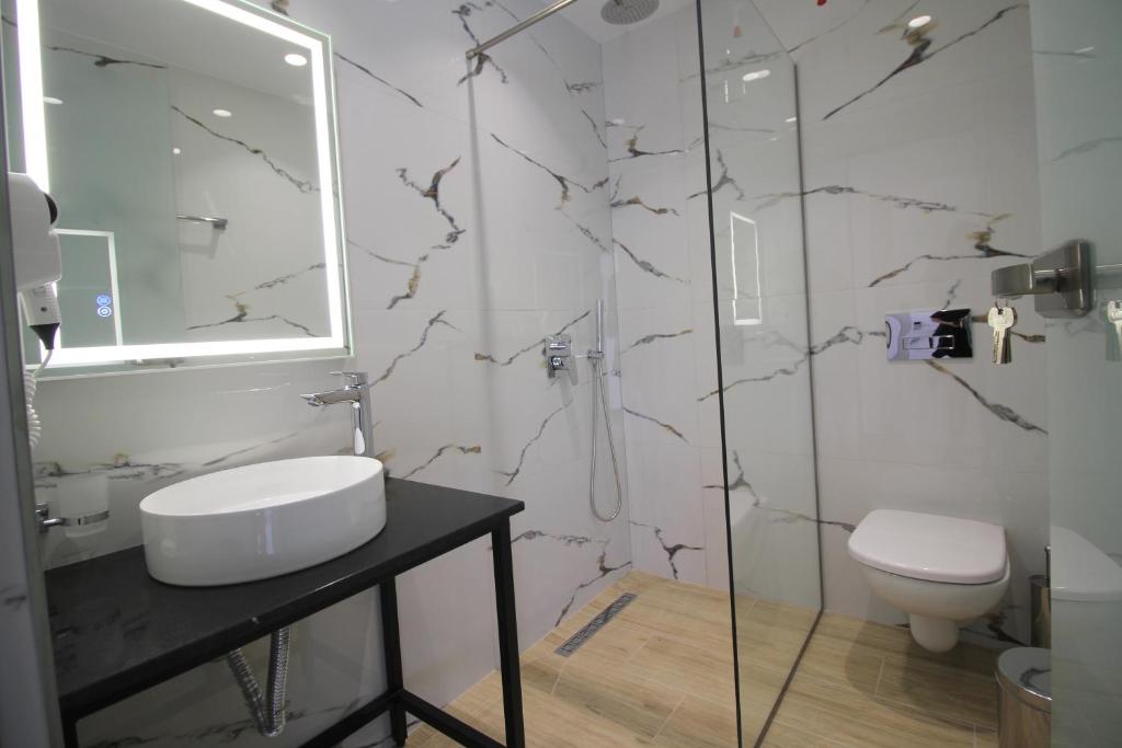 a bathroom with a toilet and a sink and a shower at Julia Hotel in Sarandë