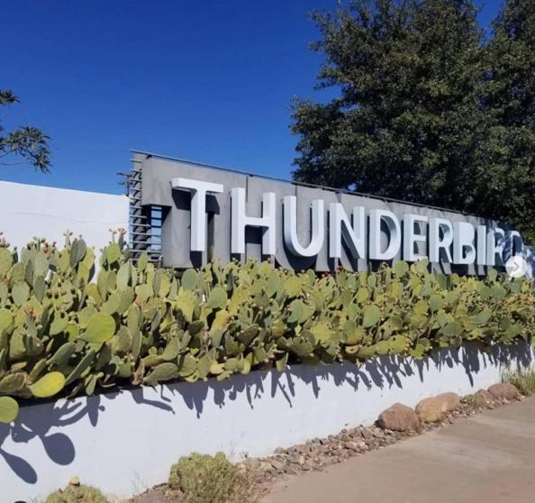 un cartello di fronte a un edificio con piante di Thunderbird Hotel a Marfa