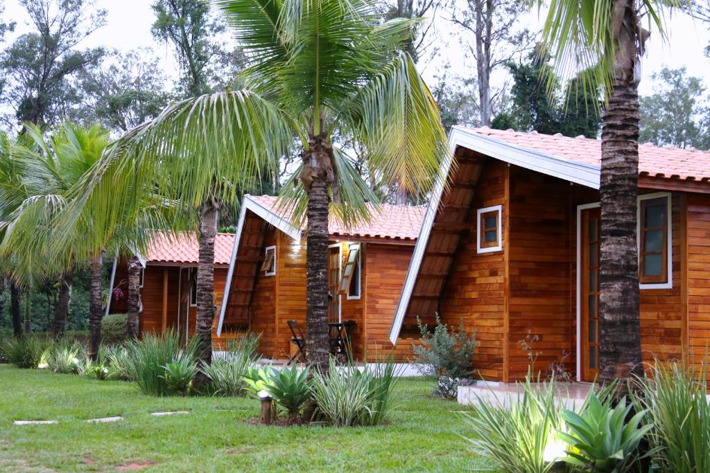 a wooden house with a palm tree in front of it at Monte Carlo Pousada in Olímpia