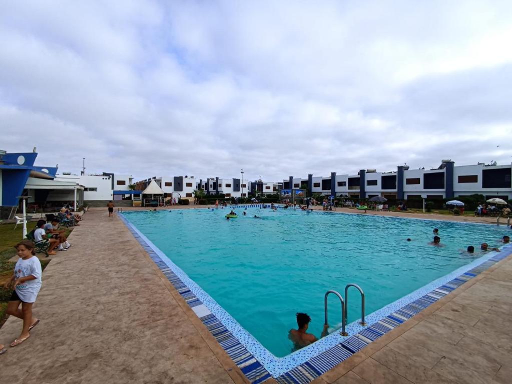 een groot zwembad met veel mensen erin bij amicale ilyass beach sidi rhal in Dar Hamida