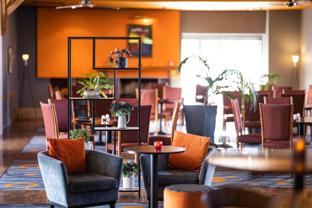 a dining room with tables and chairs and a room with orange walls at Millennium Hotel Rotorua in Rotorua