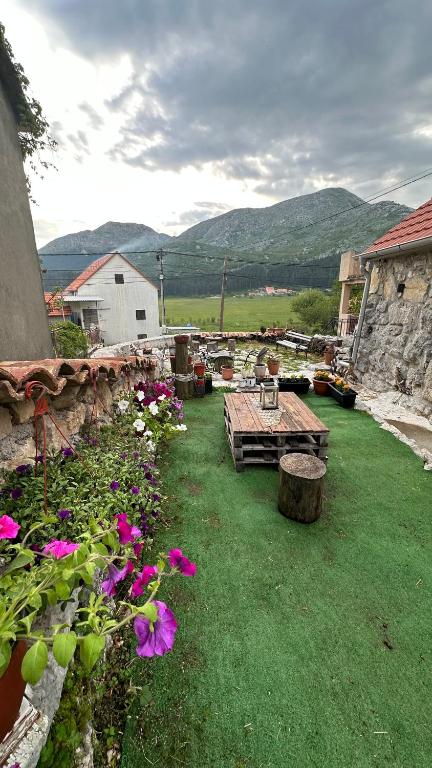 ogród z drewnianym stołem i kwiatami w obiekcie Rustic house Pojata w mieście Njeguši