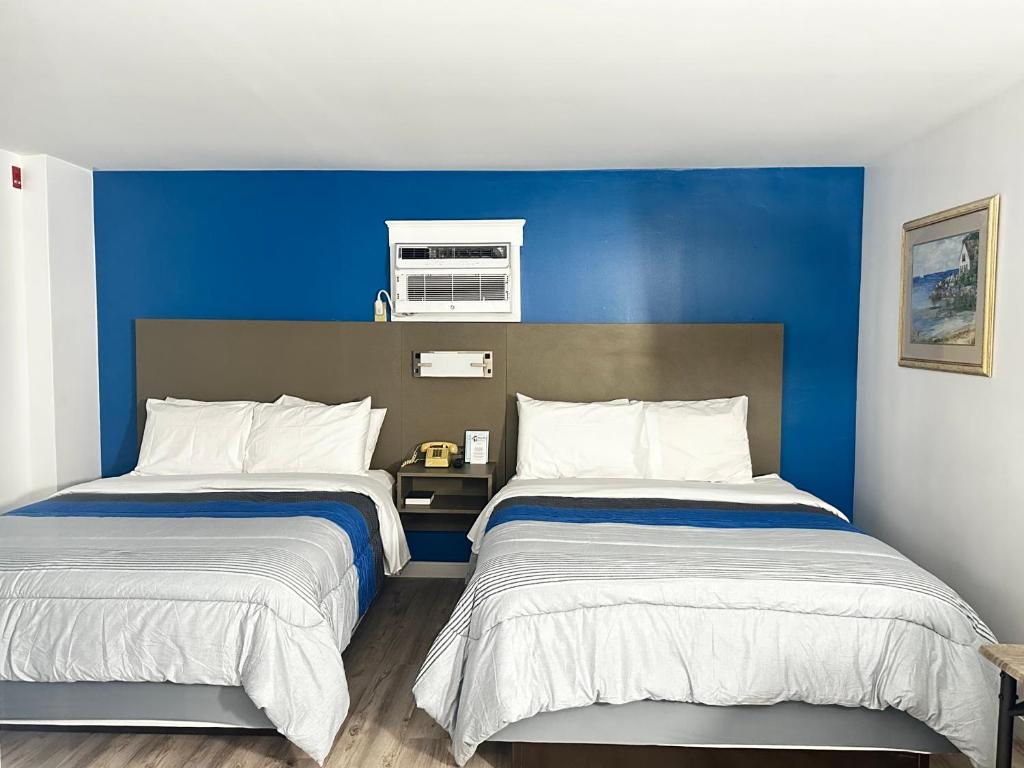 twee bedden in een kamer met een blauwe muur bij Blue Spruce Inn & Townhouses in Plymouth