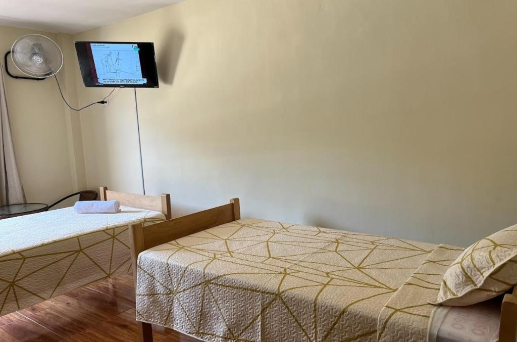 a bedroom with a bed and a tv on the wall at Hospedaje La Posada del Chino in Los Órganos
