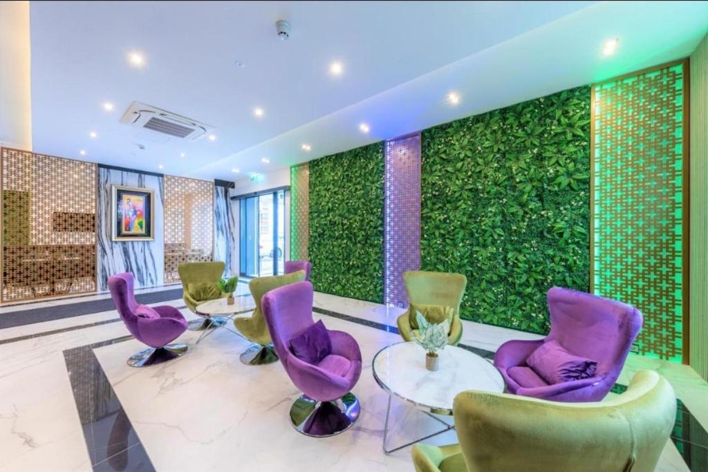 ジンデルフィンゲンにあるHotel Business Bay das ehemalige Staycation Hotelの紫色の椅子と緑の壁が特徴の客室