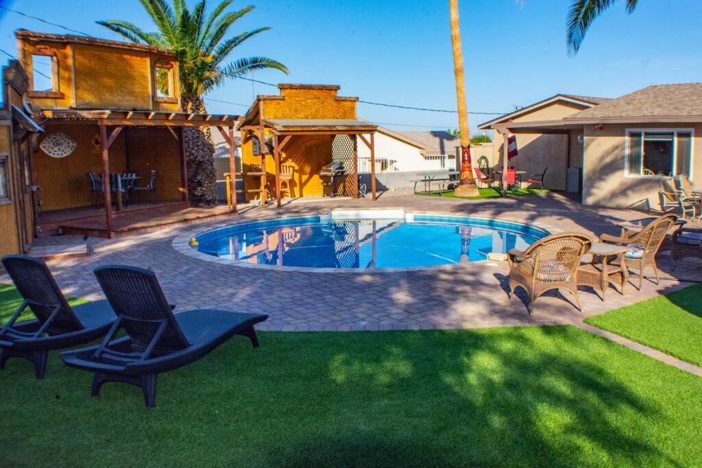 a swimming pool in a yard with chairs and a house at Good vibes, amazing backyard, plenty of parking in Lake Havasu City