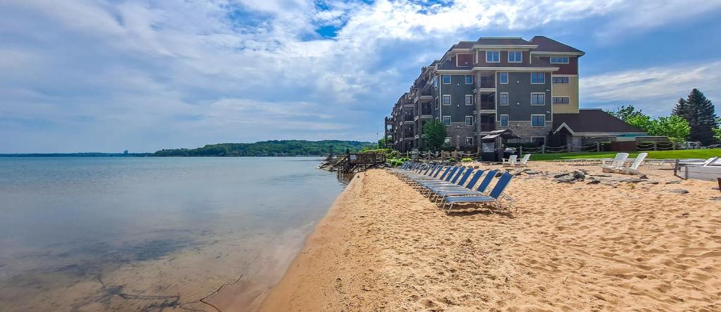 a beach with chairs and a building on the water at Tamarack Lodge in Traverse City