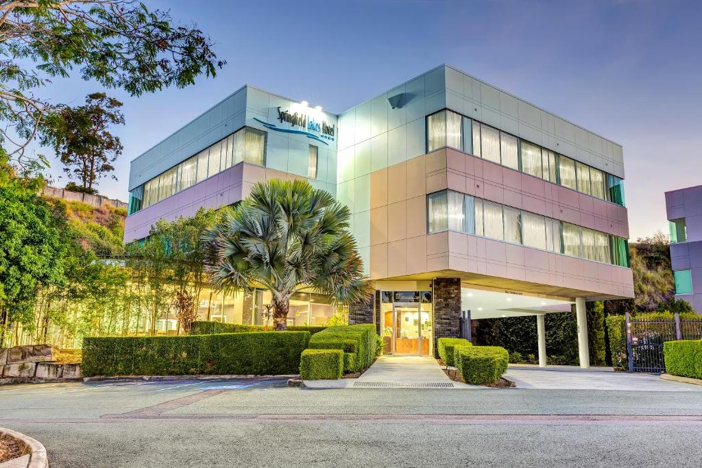 a tall building with a palm tree in front of it at Springfield Lakes Boutique Hotel in Springfield Lakes