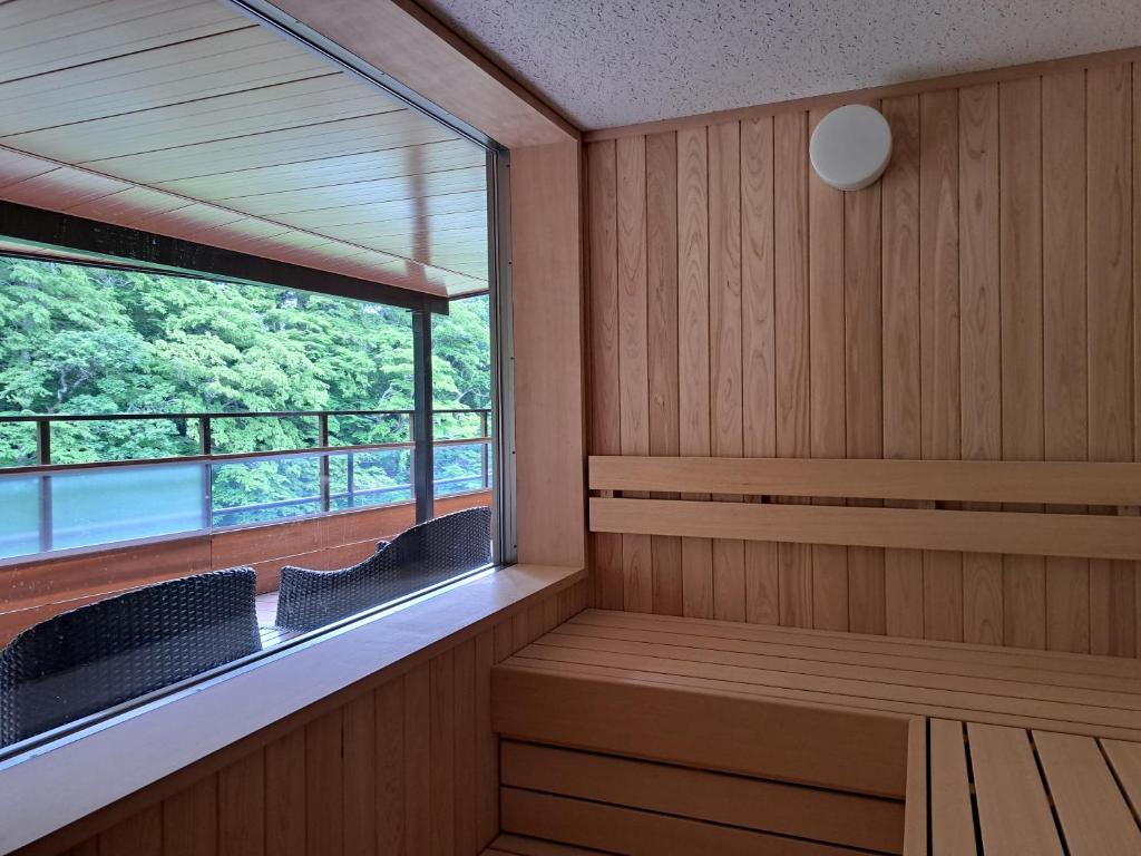 a sauna with two chairs and a large window at Shiobara Onsen Ryokan Kamiaizuya in Nasushiobara