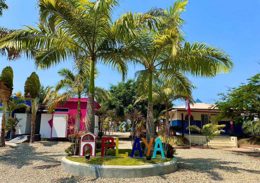 un parque con palmeras y un parque infantil en Hotel Casa Playa Zorritos en Zorritos
