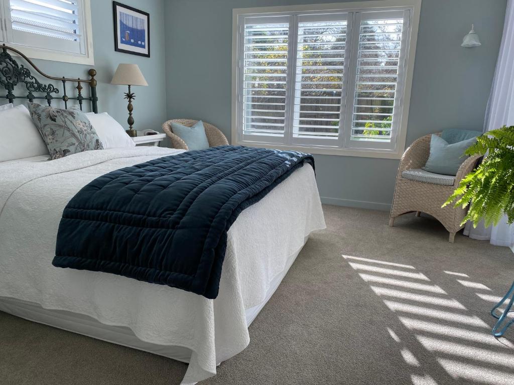 a bedroom with a bed with a blue blanket on it at Tregandale in Greytown