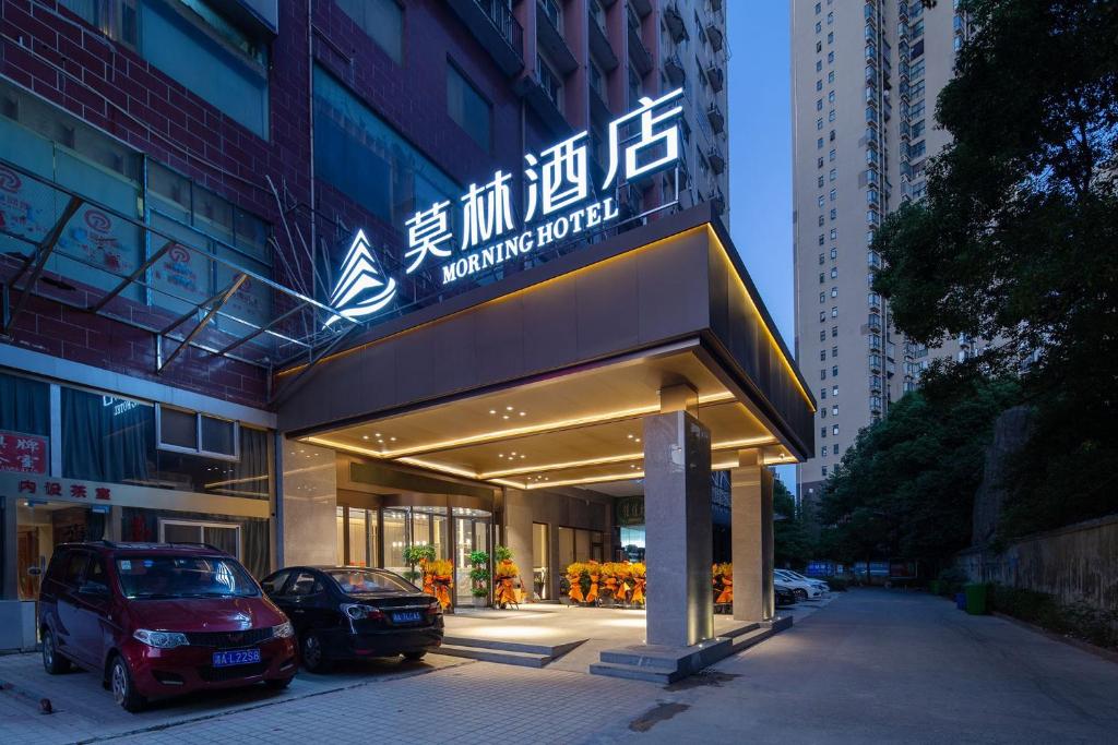 a building with two cars parked in front of it at Morning Hotel, Changsha Wanjiali Plaza Gaoqiao Metro Station in Changsha