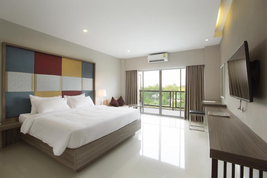 V Hotel Ubon Ratchathani في أوبون راتشاثاني: غرفة نوم بسرير كبير وبلكونة
