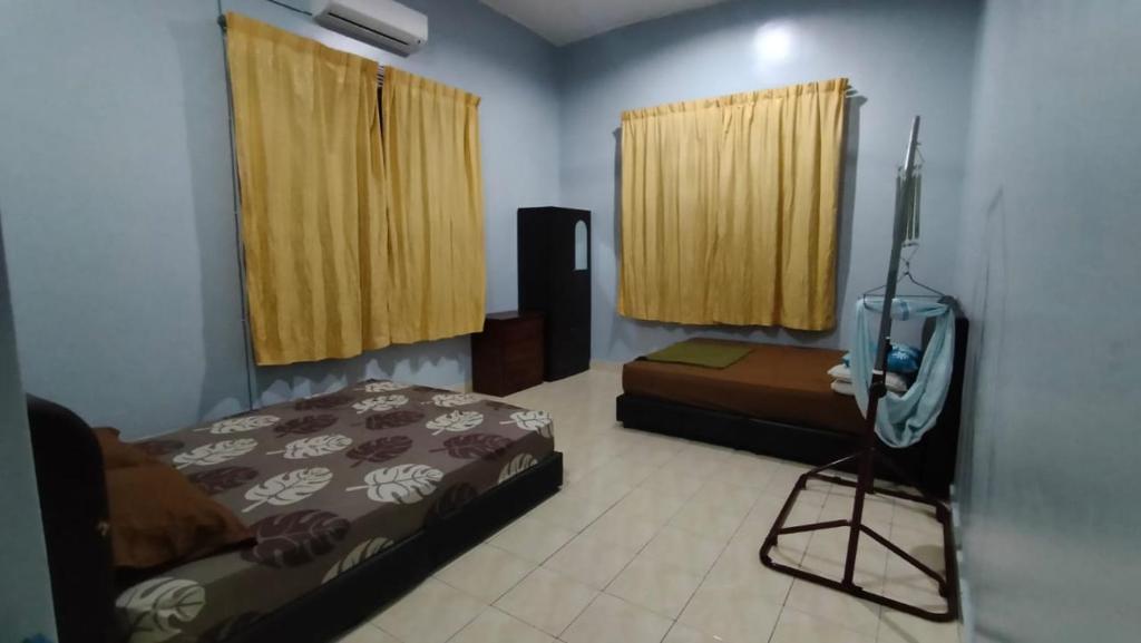 a room with two beds and a television in it at Rosspine Homestay in Jitra
