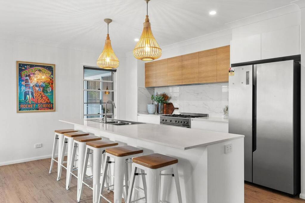 a kitchen with a counter with stools and a refrigerator at Blue Tide in Lennox Head