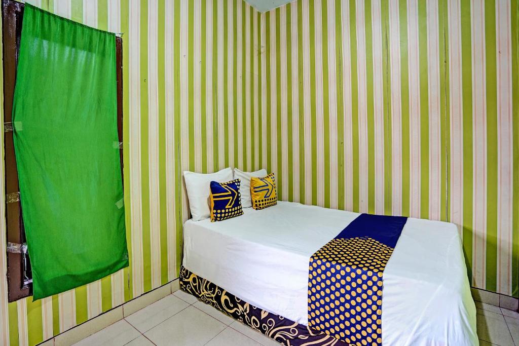 - une chambre avec un lit à rayures vertes et jaunes dans l'établissement SPOT ON 92673 Gang Songo Syariah Homestay, à Banyuwangi