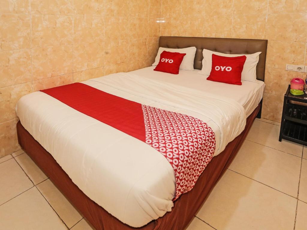 ein Bett mit zwei roten Kissen darüber in der Unterkunft SUPER OYO 92672 Hotel Bsd in South Tangerang