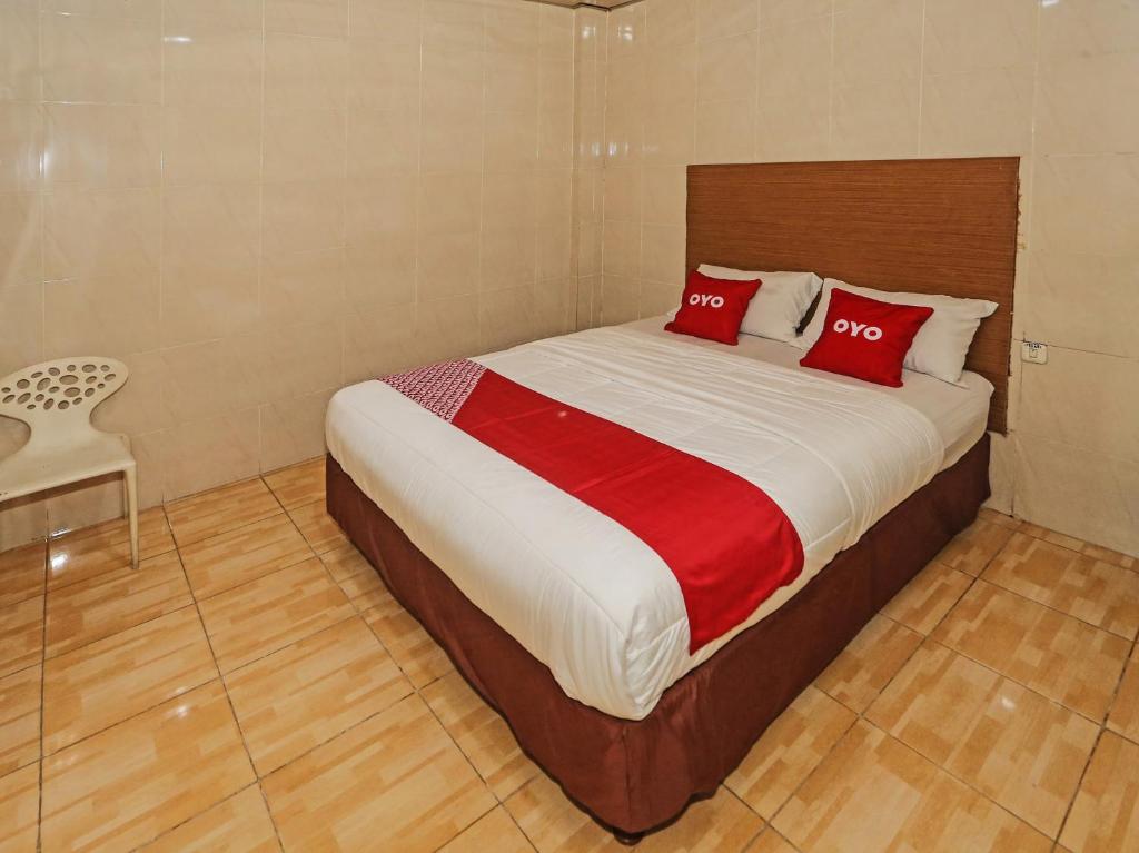 a bedroom with a bed with two red pillows at OYO 92674 Hotel Ciputat in South Tangerang