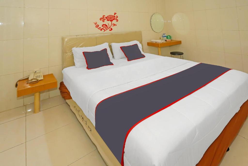 a bedroom with a large bed with two pillows at Super OYO Capital O 92676 Hotel Sion Holiday in South Tangerang