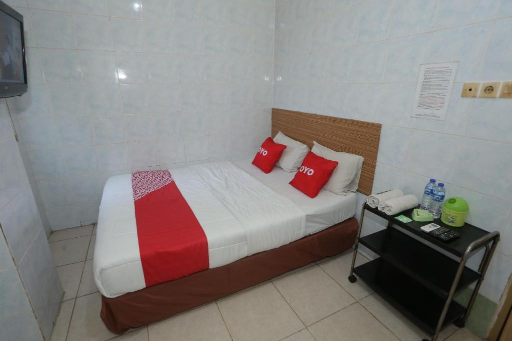 a small bedroom with a bed with red pillows at OYO 92677 Hotel Bintaro in South Tangerang