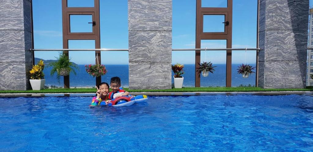 twee kinderen op een vlot in een zwembad bij Martin Ho Danang hotel & apartment in Da Nang