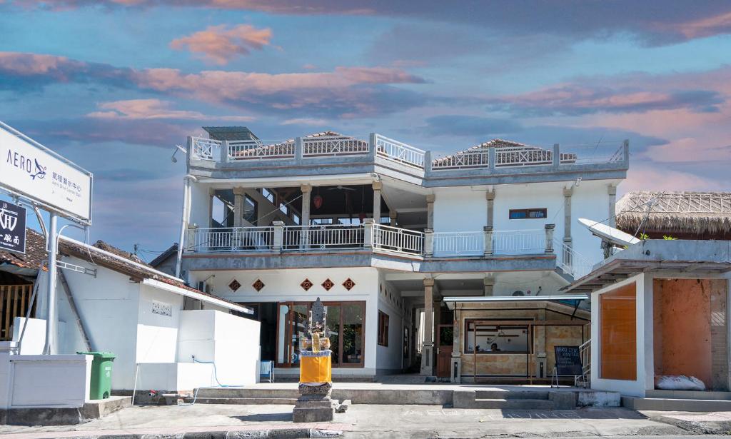 a large white building with a balcony on a street at Dive &amp; Dwell Tulamben in Tulamben