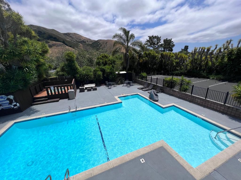 a large swimming pool in a yard with mountains in the background at Inn at San Luis Obispo in San Luis Obispo