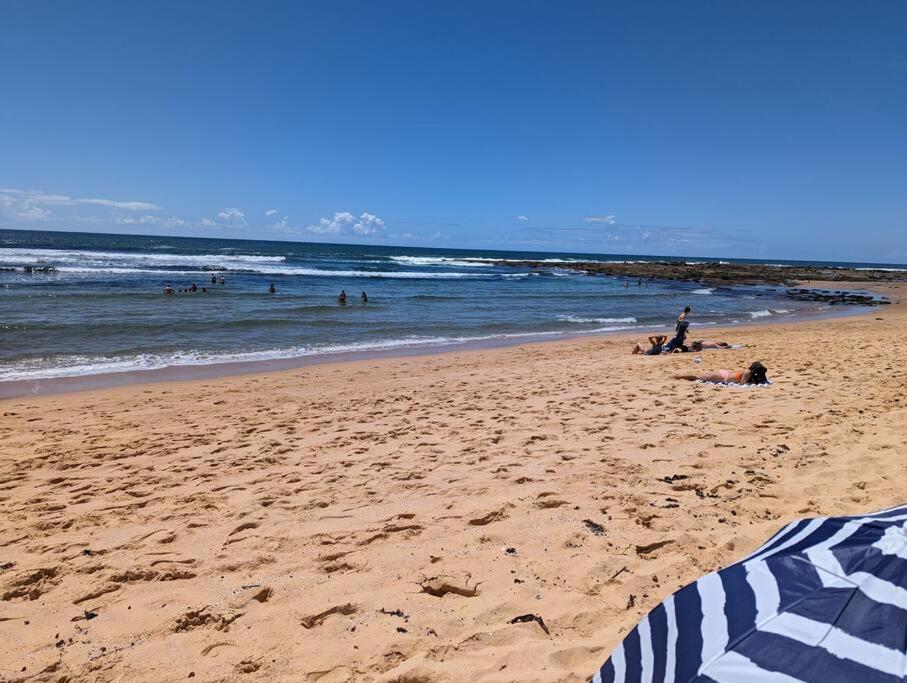 a group of people on a beach with the ocean at Bateau Bay Retreat in Bateau Bay