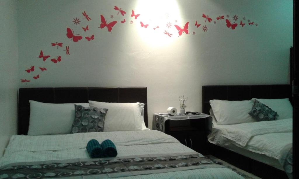 een slaapkamer met 2 bedden en vlinders aan de muur bij Best Seven Inn in Kuah