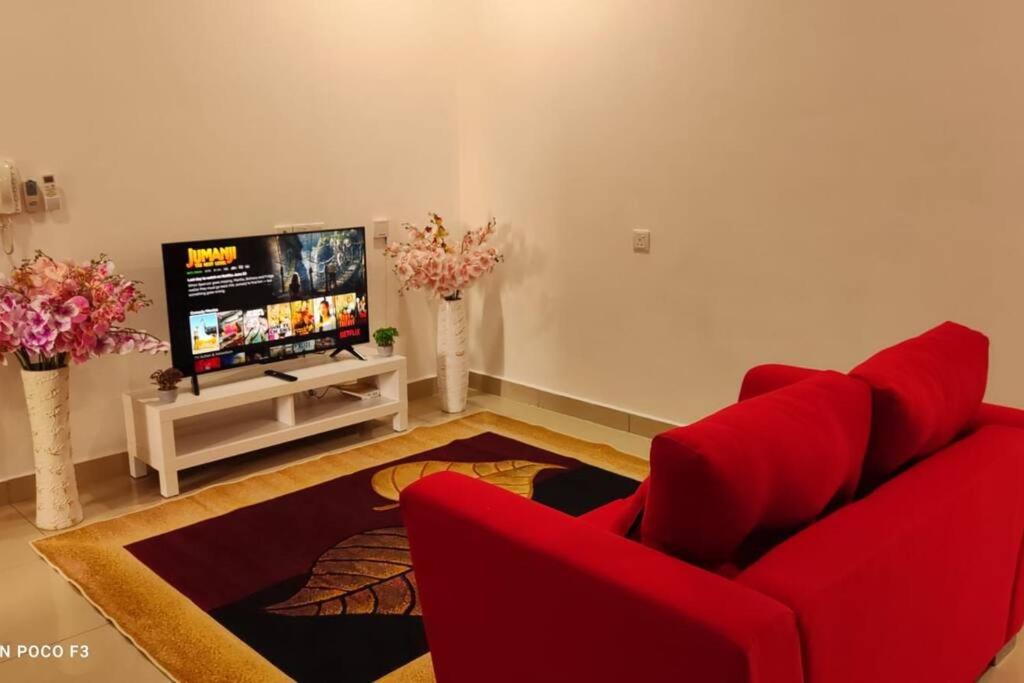 sala de estar con sofá rojo y TV de pantalla plana en HA1605- 2 BEDROOM- WI-FI-NETFLIX-PARKING- CYBERJAYa, 3077, en Cyberjaya
