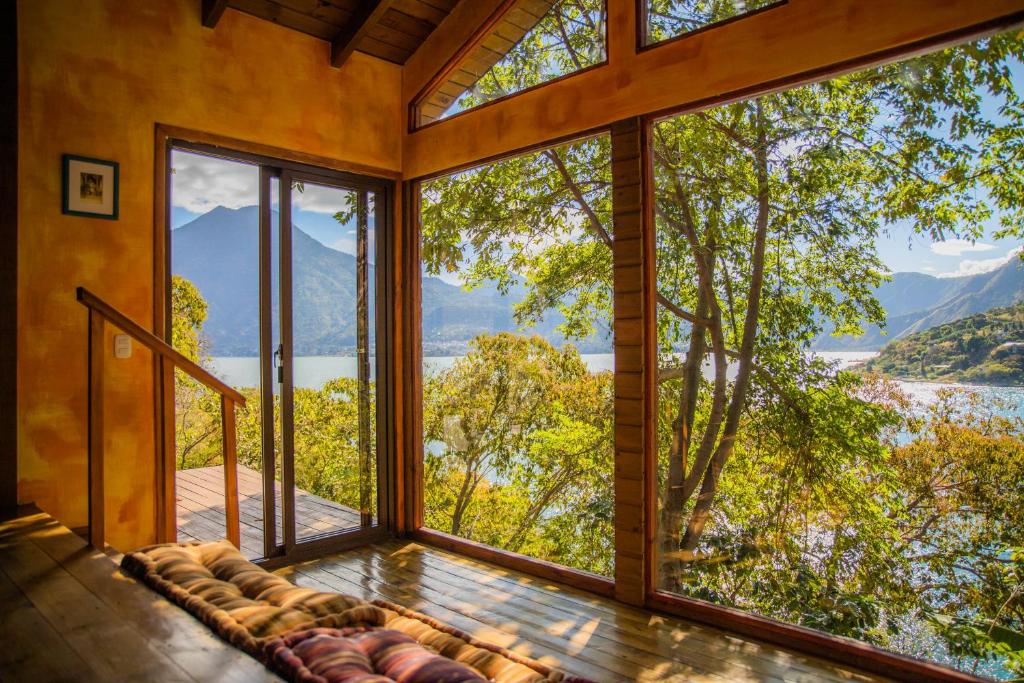 a room with large windows with a view of a lake at Baba Yaga Atitlan in San Marcos La Laguna