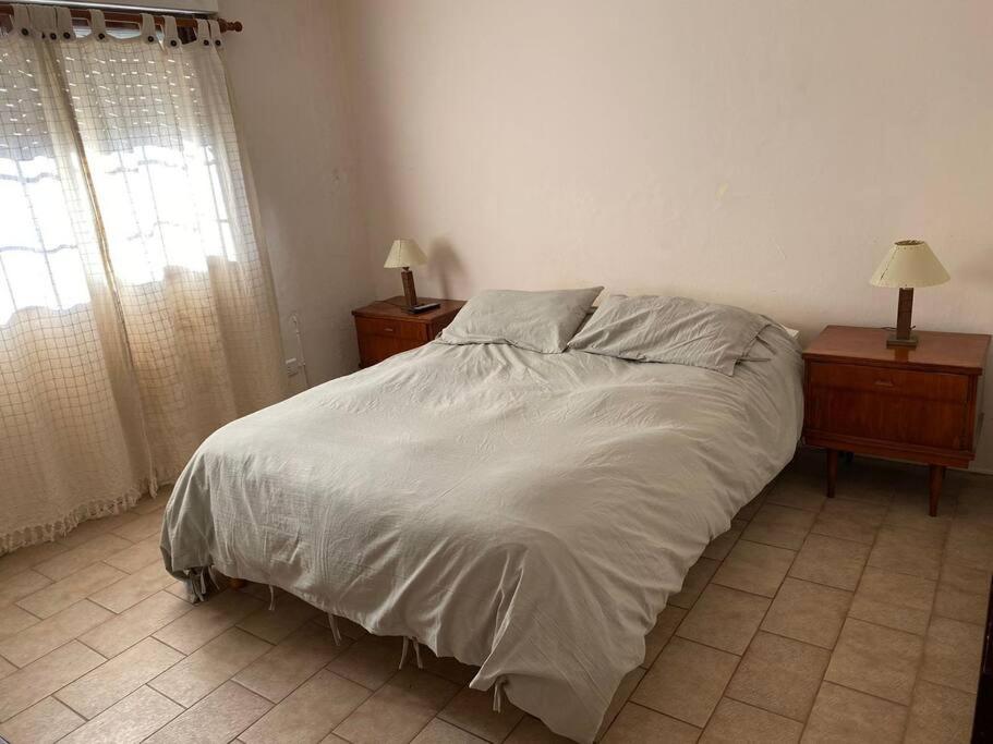 1 dormitorio con 1 cama, 2 mesitas de noche y ventana en Villegas Centro en Coronel Suárez
