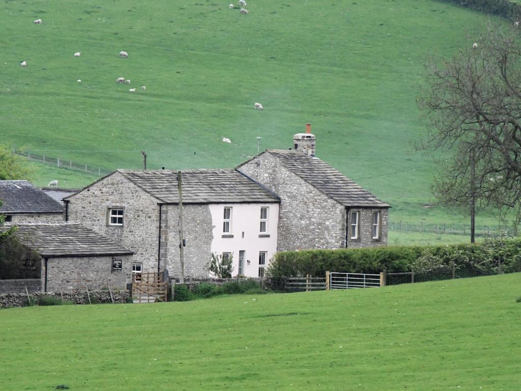 una vieja casa de piedra en un campo de hierba en 3 Hull House Cottage, en Skipton