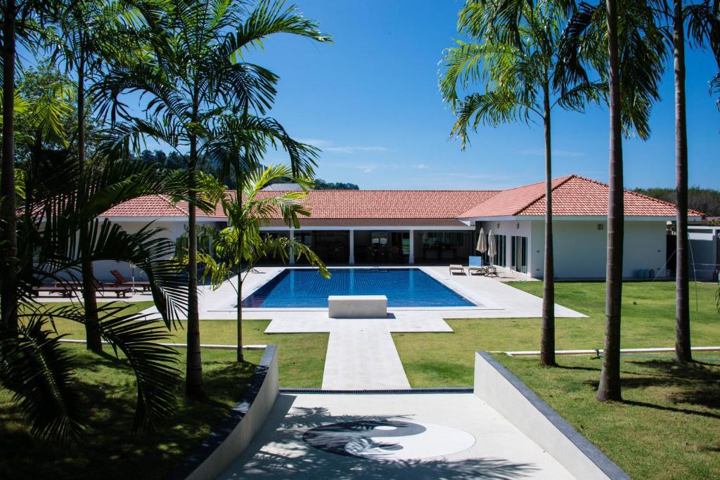 una casa con piscina y palmeras en Villa Tha Maphrao, en Ban Pa Khlok
