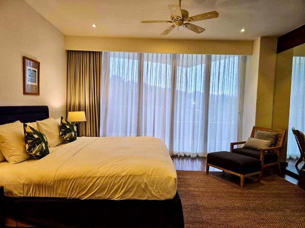um quarto com uma cama, uma ventoinha e uma cadeira em Beachfront 2 BR Luxury Apartment Chava Surin em Praia de Surin