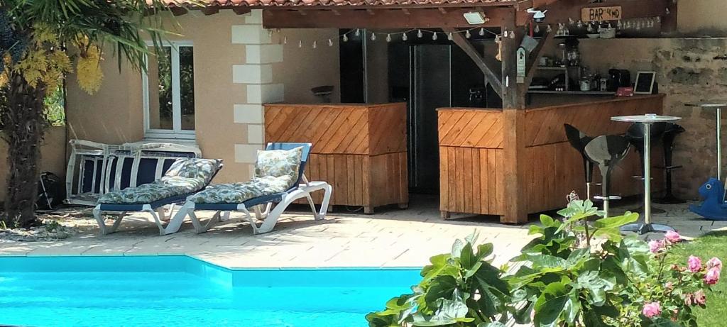 a patio with two chairs next to a pool at Les dodos de Rose in Doué-la-Fontaine