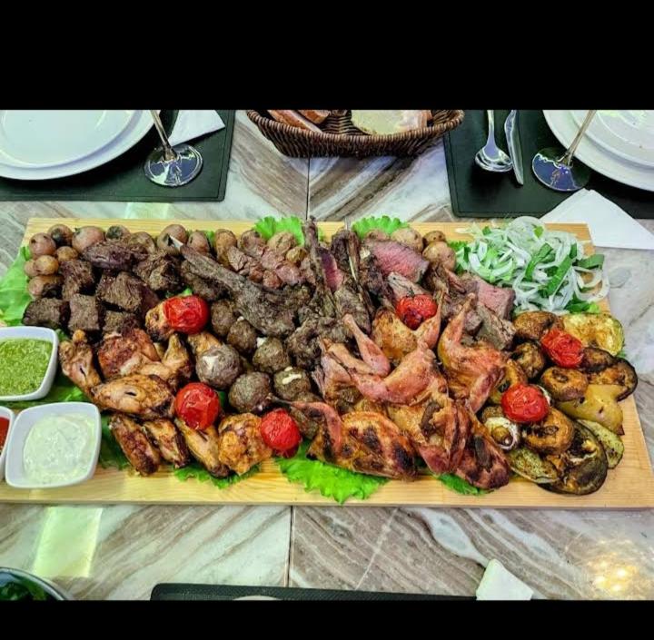 a platter of meat and vegetables on a table at Апартамент в центре города Худжанд in Khujand
