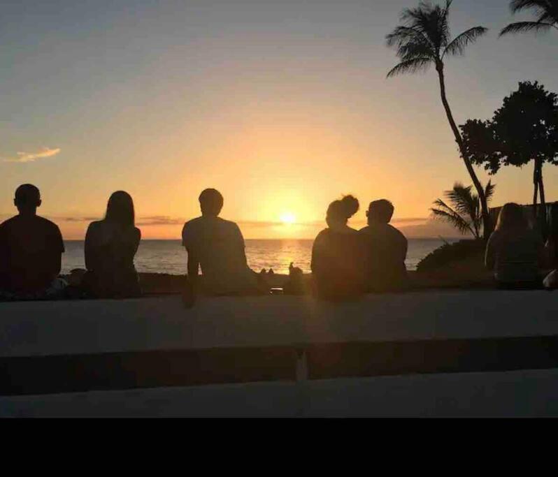 基黑的住宿－Unrivaled S Kihei Maui location! Walk to it all!，一群人坐在墙上,看着日落