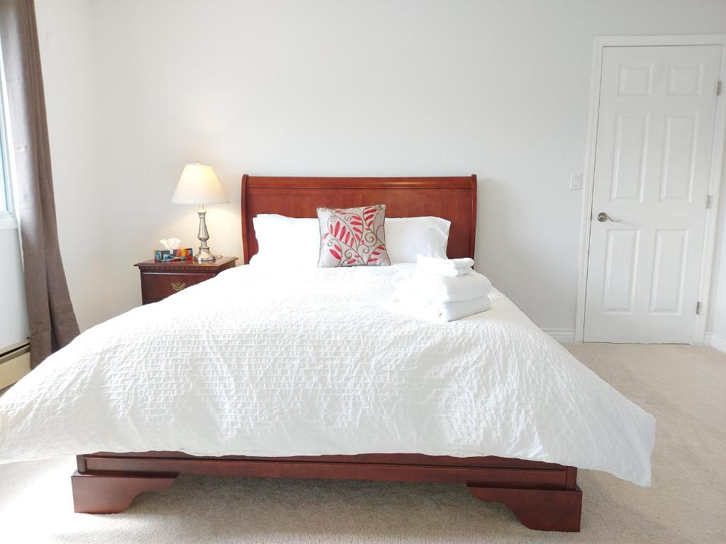 a bedroom with a white bed with a wooden headboard at Tranquil Retreat Spacious 2-Bedroom on a Serene Acreage in Kelowna