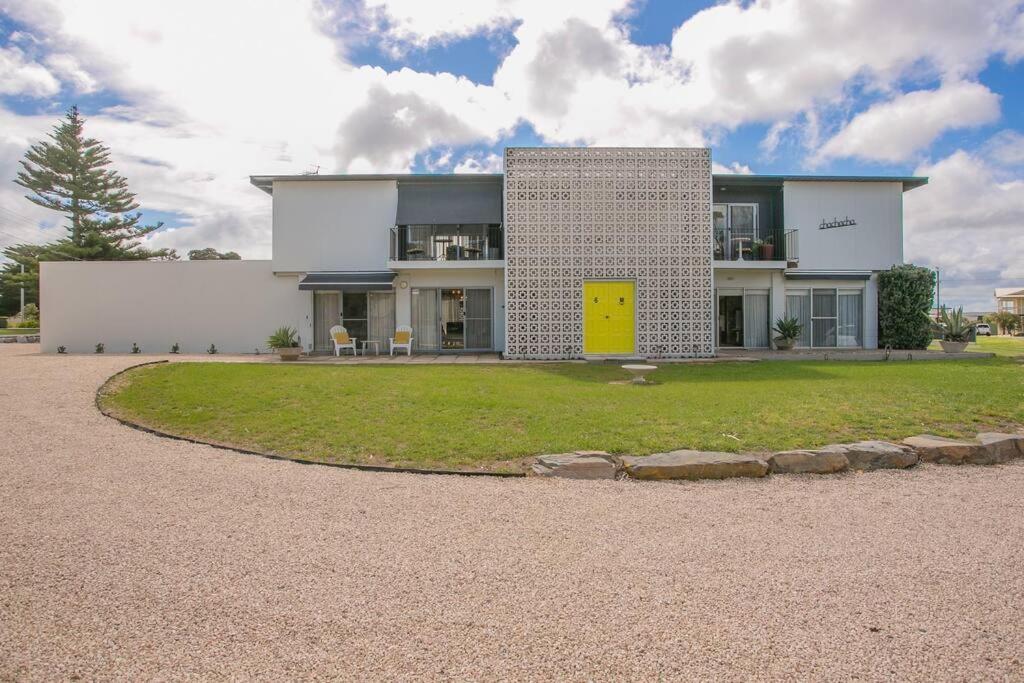 a white house with a yellow door on a yard at Que Sera Sera in Goolwa South