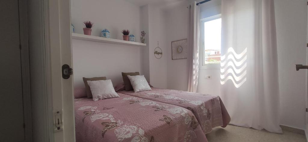 a bedroom with a bed with a pink blanket and a window at PC CHICLANA, PARKING, WIFI, aire, confort in Chiclana de la Frontera