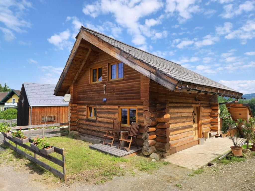 eine Blockhütte mit einer Veranda und 2 Stühlen in der Unterkunft Experience this unique wooden house! in Seltenheim