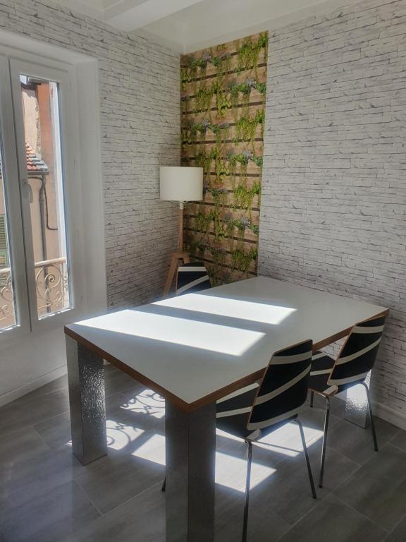 a table and chairs in a room with a brick wall at La Baieta in Moulinet