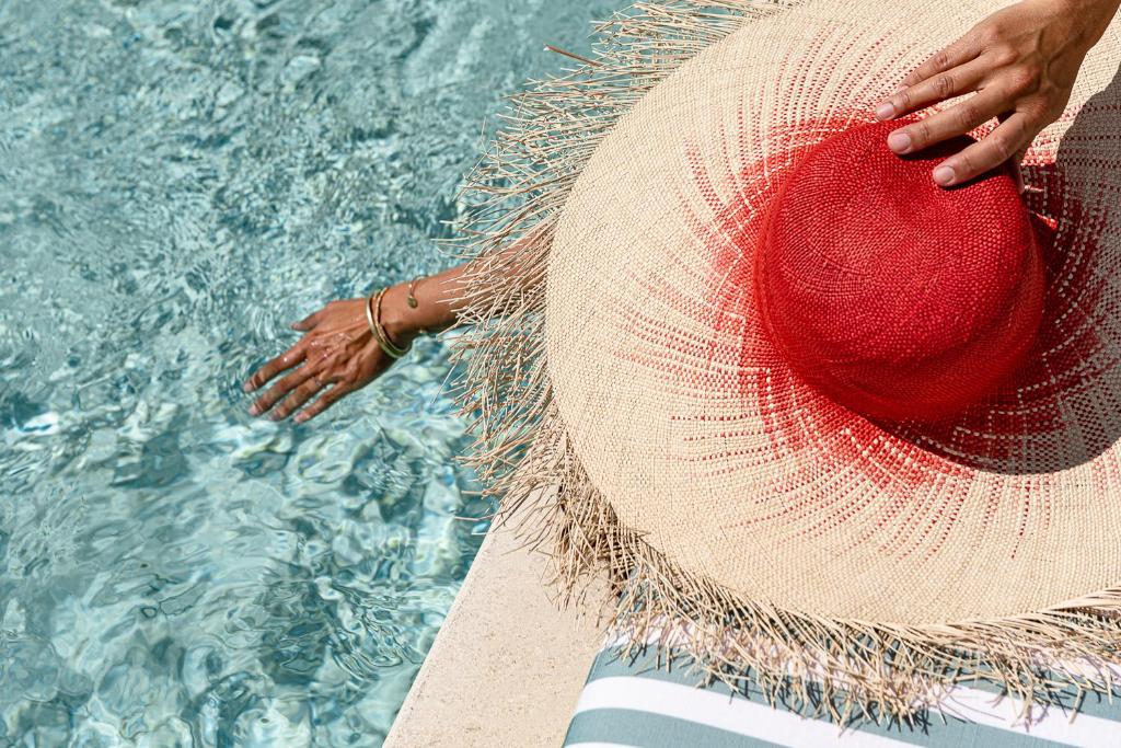 a person wearing a straw hat next to a swimming pool at Regina Experimental Biarritz in Biarritz