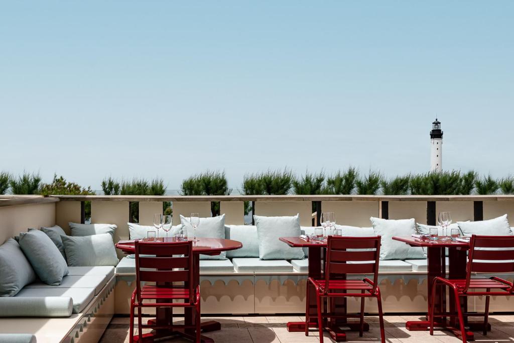 a patio with red chairs and tables on a roof at Regina Experimental Biarritz in Biarritz