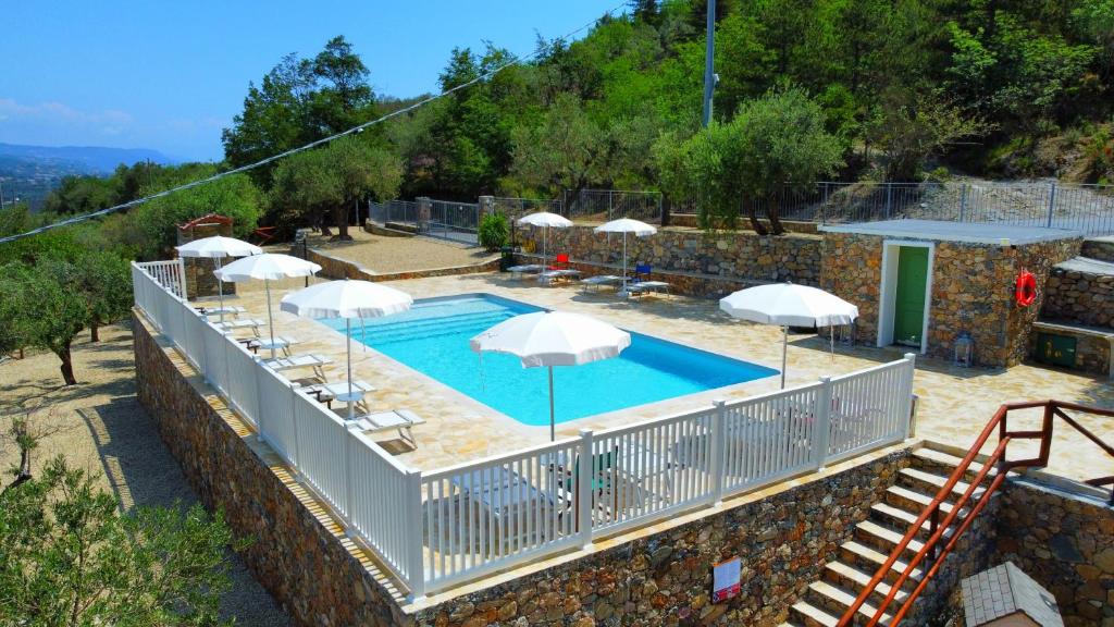 a swimming pool with white umbrellas and chairs at Agriturismo Monte Acuto - natura, mare & relax in piscina in Toirano