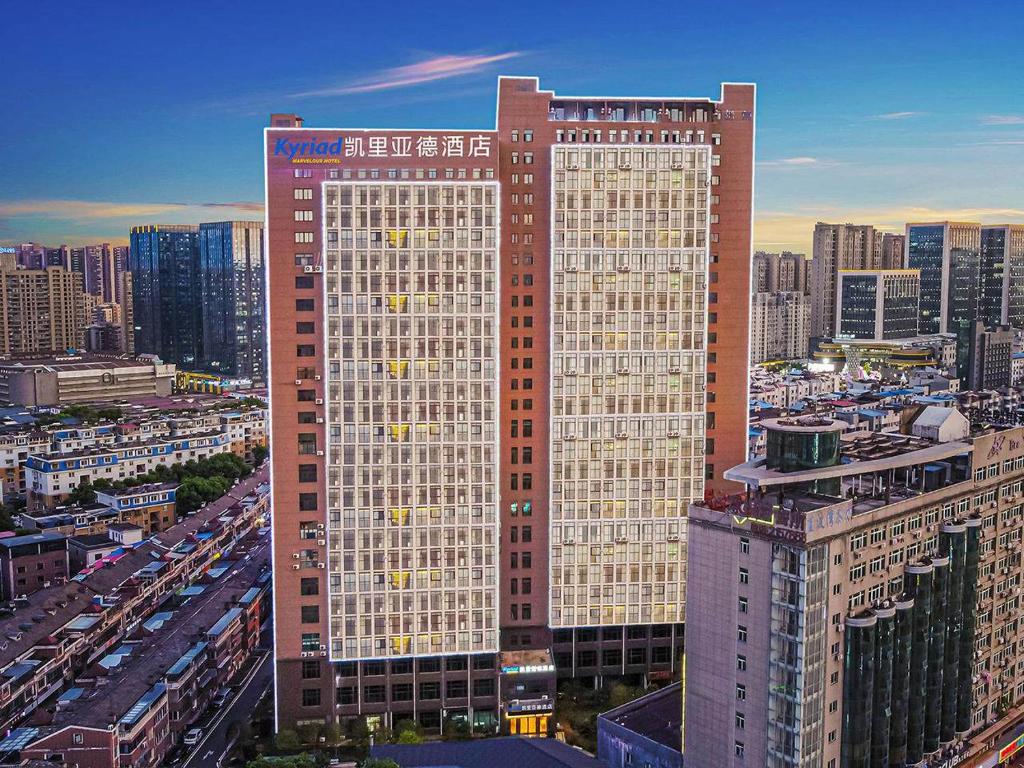 a large tall building in a city with buildings at Kyriad Hotel Jiujiang Happy City in Jiujiang
