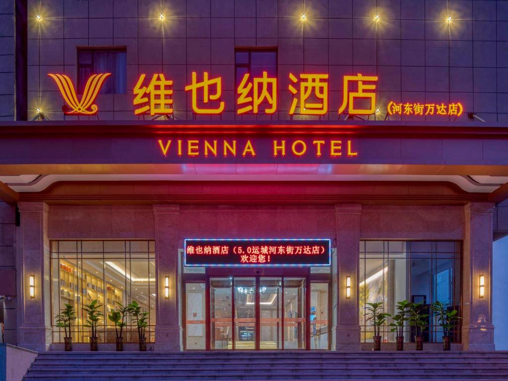 a hotel with a neon sign in front of it at Vienna Hotels Yuncheng Hedong Street Wanda Store in Yuncheng