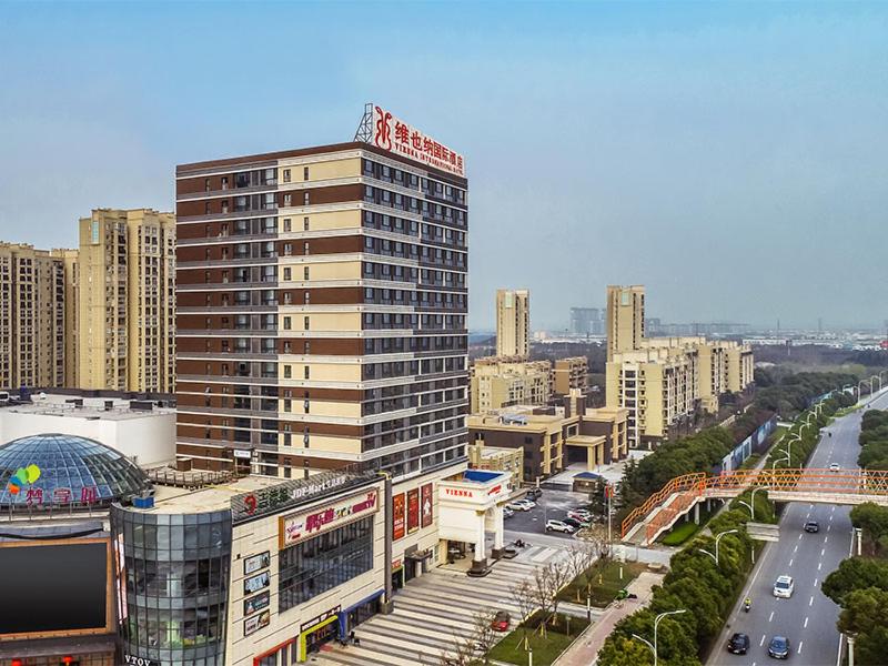 a large tall building in a city with traffic at Vienna International Hotel Wuxi Huishan Yanqiao Metro Station in Wuxi
